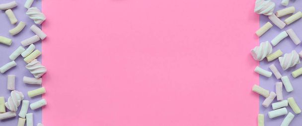 Πολύχρωμο marshmallow ορίζονται σε βιολετί και ροζ χαρτί υπόβαθρο. παστέλ δημιουργική υφή πλαίσιο. ελάχιστη. - Φωτογραφία, εικόνα