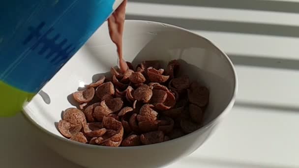 Movimento lento di versare il latte di cacao in un fiocchi di mais al cioccolato in ciotola
 - Filmati, video