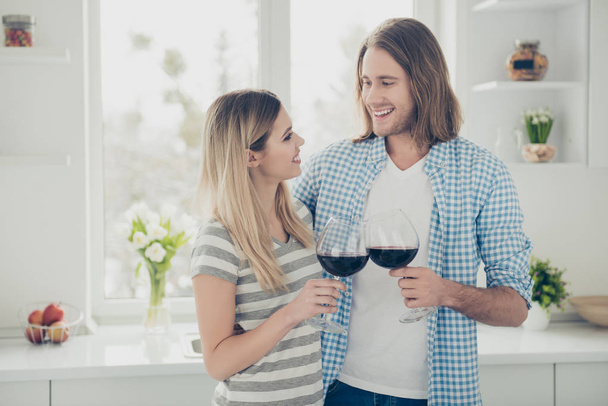 Portrait of lovely romantic couple spending weekend indoor looking at each other drinking red wine clinking glasses enjoying holiday. Idyllic daydream delight concept - Photo, image