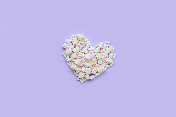 Marshmallow colorido dispuesto sobre fondo de papel violeta y rosa. corazón texturizado creativo pastel. mínimo
. - Foto, imagen