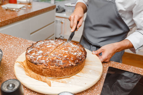 Chef-kok handen maken laatste raakt aan heerlijke taart gesneden op een rustieke keukentafel - Foto, afbeelding