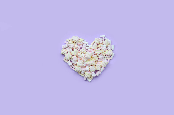 Πολύχρωμο marshmallow ορίζονται σε βιολετί και ροζ χαρτί υπόβαθρο. παστέλ δημιουργική ελαστικοποιημένων καρδιά. ελάχιστη. - Φωτογραφία, εικόνα