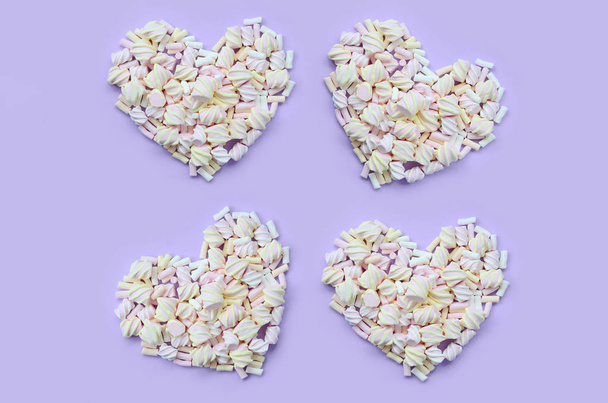Marshmallow colorido dispuesto sobre fondo de papel violeta y rosa. pastel corazones texturizados creativos. mínimo
. - Foto, Imagen