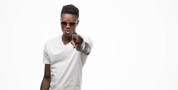Fiatal afroamerikai férfi mutató ujjával, a kamera és a kéz jel, az első pozitív és magabiztos gesztus napszemüveget visel - Fotó, kép