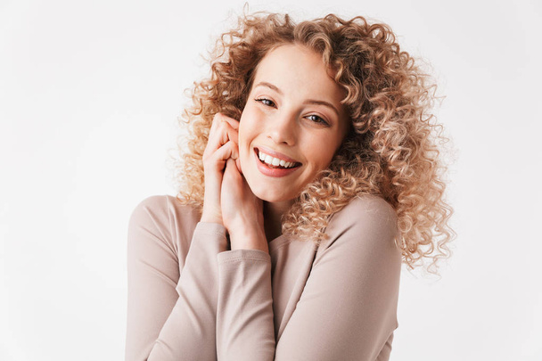 Portrait of a cheerful young curly blonde girl in dress looking at camera isolated over white background - Fotografie, Obrázek