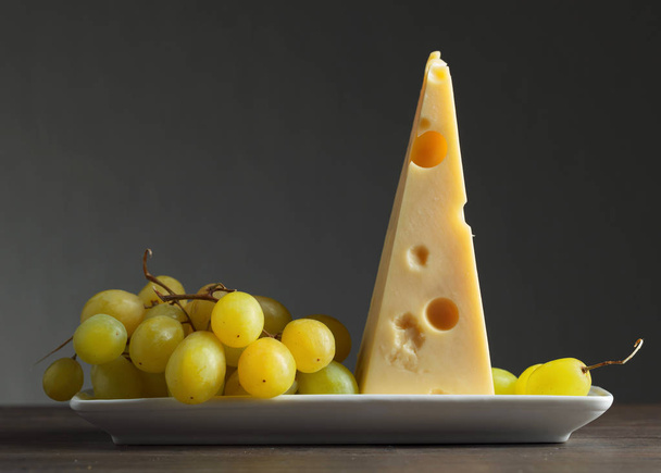 Cheese with grapes on a old wooden table. - Φωτογραφία, εικόνα