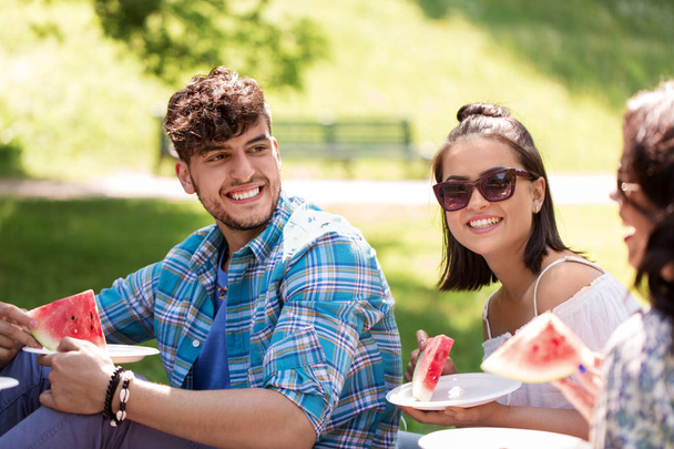 happy friends eating watermelon at summer picnic - Foto, imagen