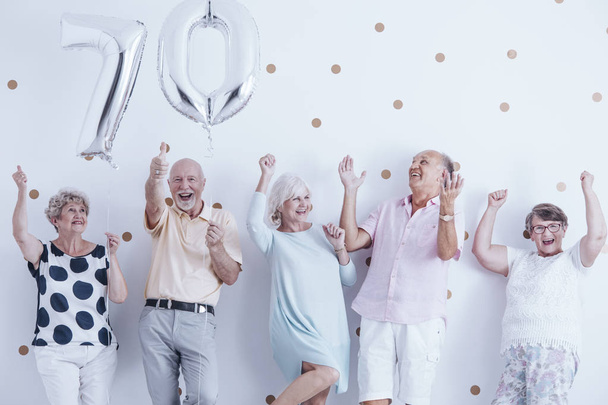 Anziani sorridenti che festeggiano con palloncini d'argento durante la festa di compleanno
 - Foto, immagini