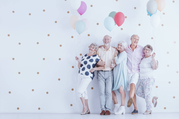 Group of enthusiastic elderly people with colorful balloons have fun during meeting - Foto, Imagem