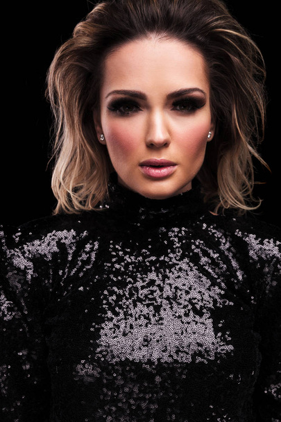 portrait of seductive woman wearing a sequined black dress standing on black background with parted lips - Foto, afbeelding