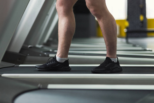 Nahaufnahme der Beine des Fitness-Manns auf dem Laufband im Fitnessstudio - Foto, Bild