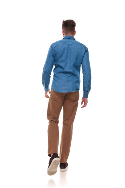 back view of young man in casual clothes walking on white background, full length picture - Photo, Image