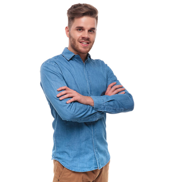 Προσωπογραφία άνδρα με αυτοπεποίθηση casual φορώντας ένα μπλε πουκάμισο στέκεται σε άσπρο φόντο με τα χέρια διπλωμένα - Φωτογραφία, εικόνα