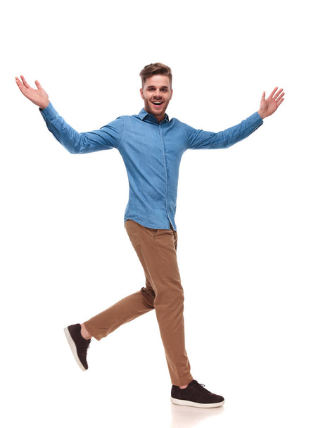 celebrando hombre casual con camisa azul camina a un lado sobre fondo blanco, imagen de cuerpo entero
 - Foto, Imagen
