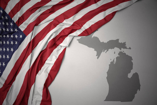waving colorful national flag of united states of america on a gray michigan state map background. - Photo, Image