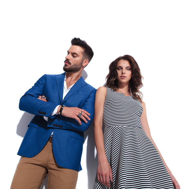 confident casual man leaning on his woman looks down to side while standing on white background, bottom angle picture - Photo, Image