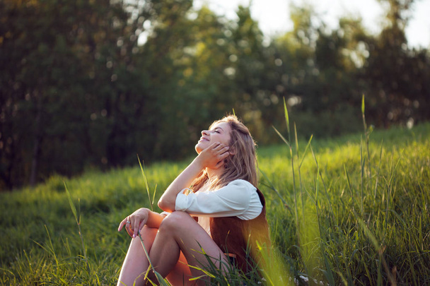 Happy woman in white shirt enjoying a picnic in nature. Girl sitting on grass, rest, relaxation - Fotoğraf, Görsel