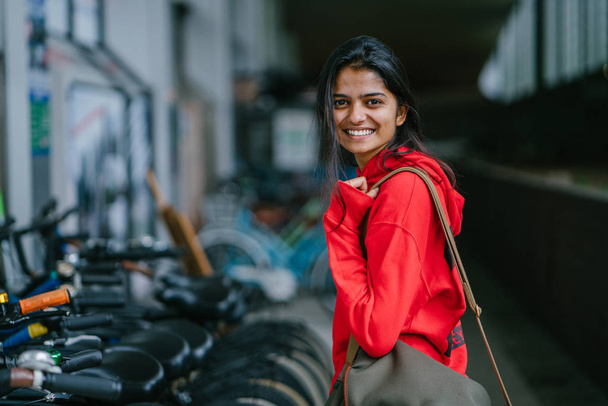 портрет усміхненої індійської дівчини, що стоїть на фоні з припаркованими велосипедами
 - Фото, зображення