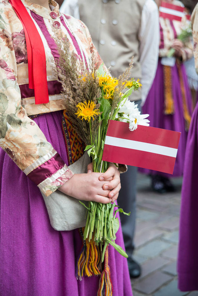 Elementos y trajes nacionales letones, personas con ramos de flores de campo en la apertura del Festival Nacional de Canción y Danza de Letonia en Riga
 - Foto, imagen