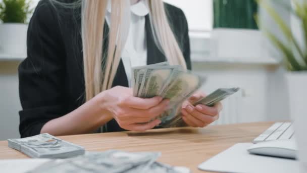 Business woman counting cash in hands. Crop view of female in elegant suit sitting at wooden desk and counting large bundle of dollar banknotes in hands. - Footage, Video