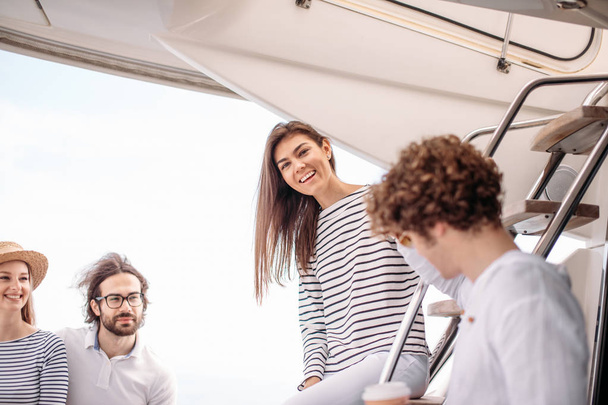 Travel, seatrip, friendship and people concept - friends sitting on yacht deck - 写真・画像