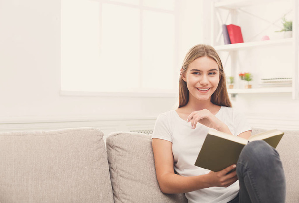 Cozy home. Young smiling woman with book - Foto, Bild