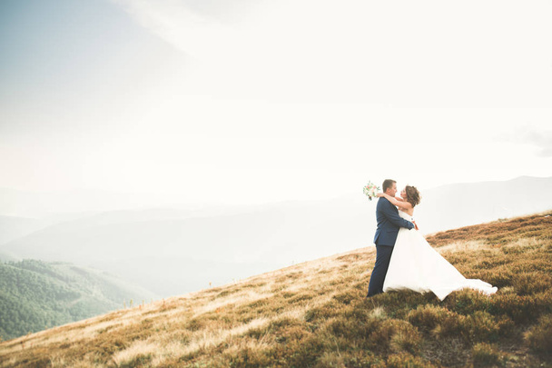 Beautiful gorgeous bride posing to groom and having fun, luxury ceremony at mountains with amazing view, space for text, wedding couple - Fotó, kép