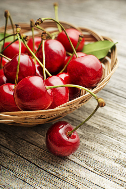 Fresh red cherries in basket on wooden table - 写真・画像