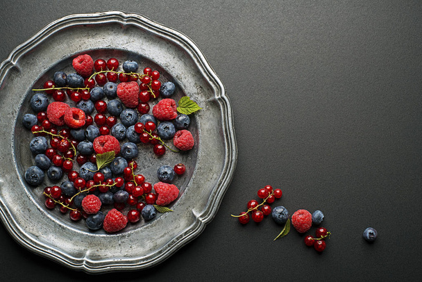 Mix of fresh berries in a plate on black background - Photo, Image