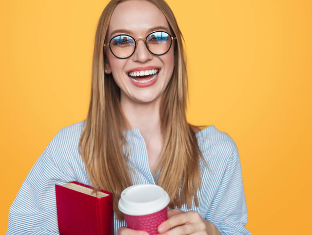 Laughing woman with beverage and book - Foto, Imagem