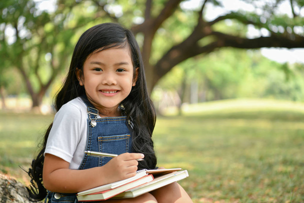 Концепции образования. Девушка читает книгу в саду. Красивая девушка серьезно учится. Красивые девушки счастливы учиться
. - Фото, изображение