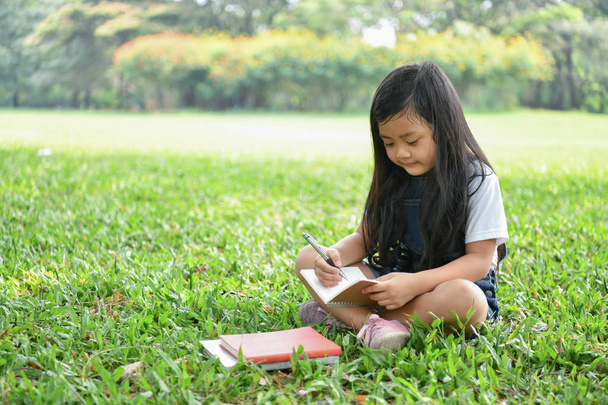 Education Concepts. The girl is reading a book in the garden. Beautiful girl is seriously studying. Beautiful girls are happy learning. - Photo, Image