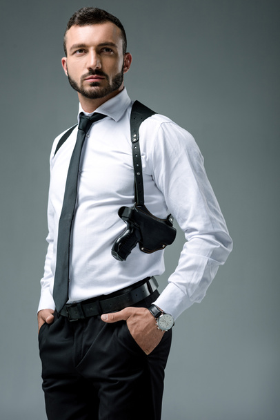 handsome security guard standing with gun isolated on grey - Fotoğraf, Görsel