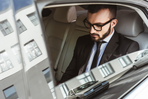 handsome businessman sitting in car and looking down - 写真・画像