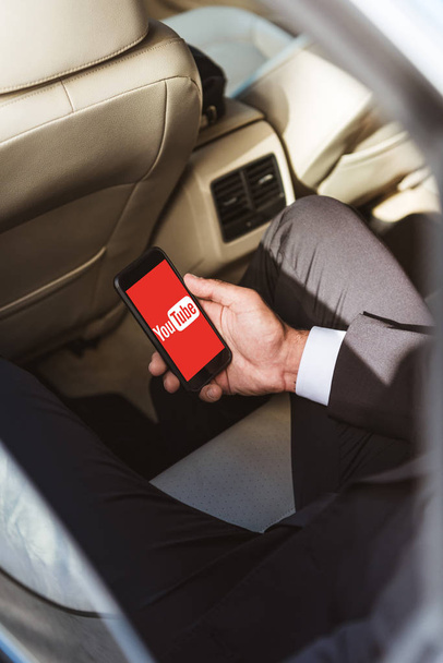 cropped image of businessman holding smartphone with loaded youtube page in car - Фото, зображення