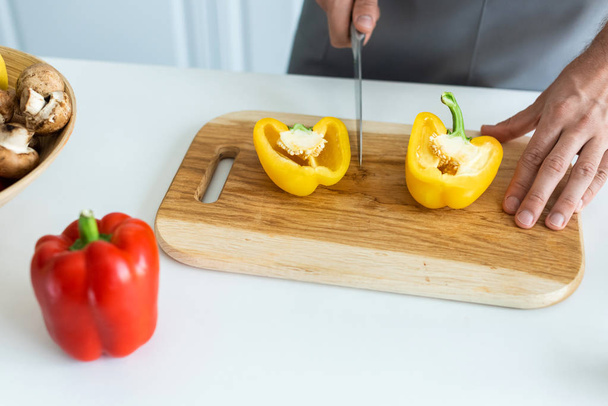 cropped shot of man cutting bell pepper on wooden cutting board - 写真・画像
