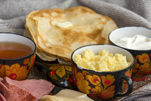 Το πρωινό στο κρεβάτι για την αγαπημένη σας, τηγανίτες με ξινή κρέμα, τυρί και κρέας, χυλό καλαμποκιού και ένα φλιτζάνι φρέσκο τσάι. Καλημέρα! - Φωτογραφία, εικόνα