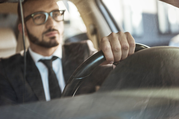 selective focus of handsome driver in suit driving car - 写真・画像