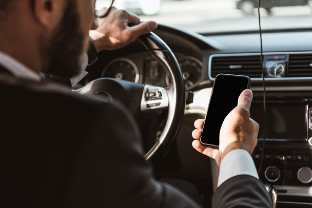 cropped image of driver in suit driving car and holding smartphone - Fotografie, Obrázek