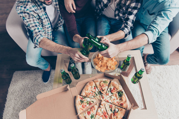 Cropped, top view portrait of stylish, attractive friends in denim, casual outfit  clinking bottls with lager for goal, community, unity having nice meeting, sitting in living room - Фото, зображення