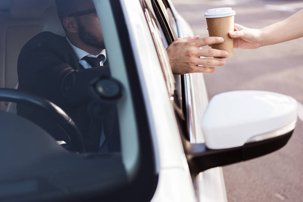 levágott kép a vezető eldobható kávéscsésze vásárol, és ül az autóban - Fotó, kép