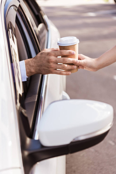 cropped image of driver buying coffee in paper cup and sitting in car - Фото, зображення