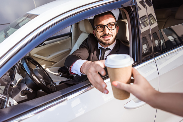 conductor guapo comprar café en taza de papel y sentado en el coche
 - Foto, imagen