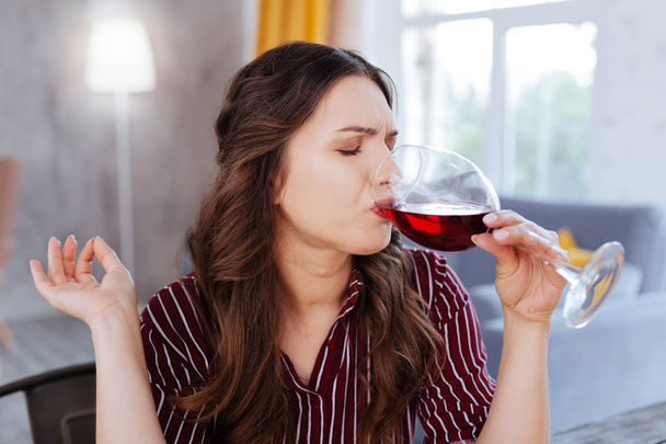 Dark-haired woman drinking wine after stress - 写真・画像