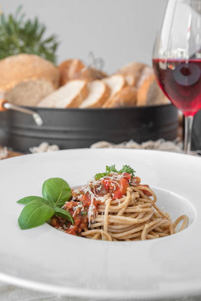 Delicious spaghetti topped with bolognaise sauce and basil served with red wine. - Фото, зображення