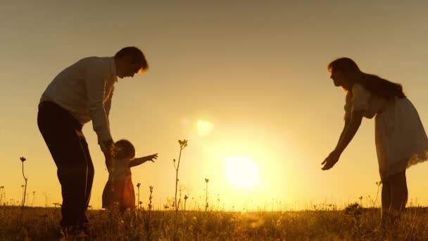 Piccolo bambino con la sua famiglia impara a camminare al tramonto. Rallentatore
. - Filmati, video