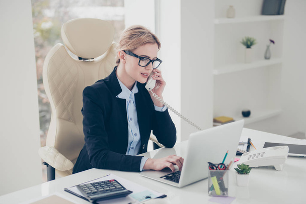 Marketing financial occupation routine concept. Portrait of smart stylish agent speaking by phone using handset typing on keyboard sitting in modern work station - 写真・画像