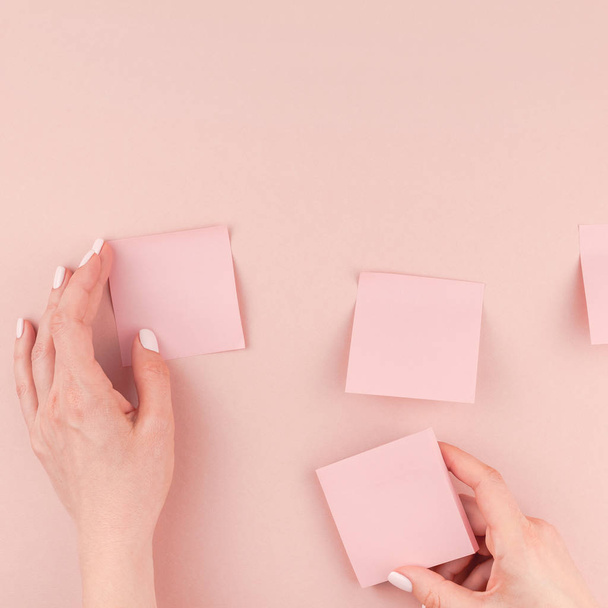 Креативная плоская фотография рабочего стола с тысячелетним розовым бумажным столбиком, который в руках женщины держит и клеит на стену с минимальным фоном пространства для копирования. Шаблон площади
 - Фото, изображение