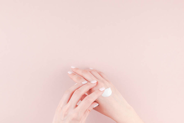 Image créative de la femme hydratant sa main avec de la crème cosmétique lotion avec espace de copie sur fond rose millénaire dans un style minimaliste. Modèle de concept blog féminin, médias sociaux, concept de beauté
 - Photo, image