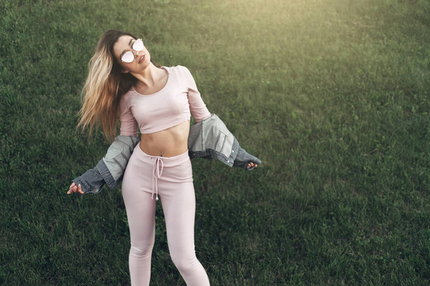 Portrait of Young and Beautiful Woman in Casual Clothes in the Street. Dressed in Pink Shirt and Pants. Spring, Summer Concept. Relax Time. Girl with Sunglasses. Enjoy City Sunset. - Photo, Image